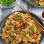 Miso Noodles served on a grey plate and garnished with green onions and tofu crumbles.