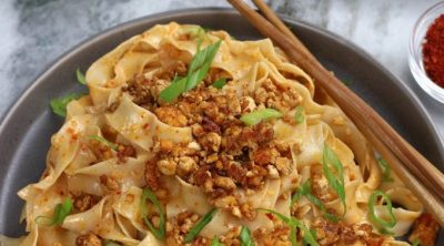 Miso Noodles served on a grey plate and garnished with green onions and tofu crumbles.