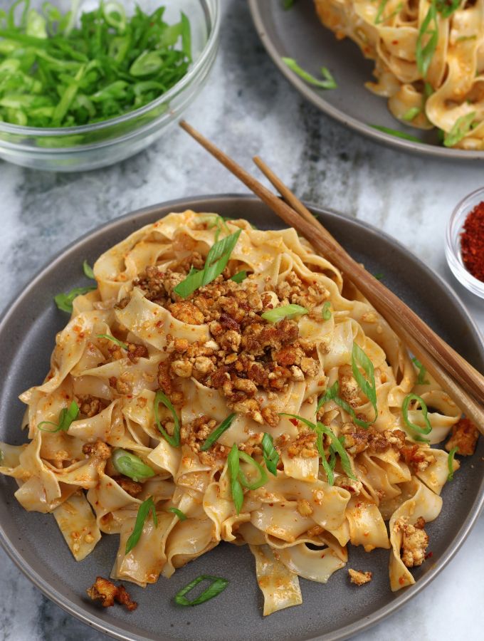 Miso Noodles served on a grey plate and garnished with green onions and tofu crumbles.