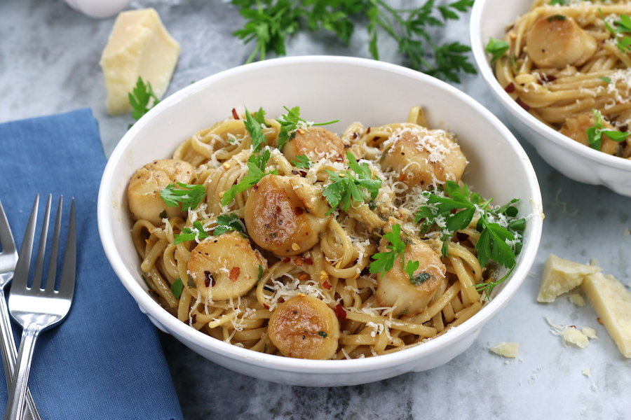 Horizontal photo of Scallops and Linguine served in pasta bowls and garnished with Italian parsley.
