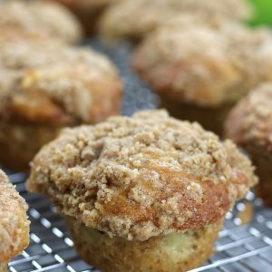 Up close vertical photo of Apple Crumble Muffins lined up on a cooling rack.