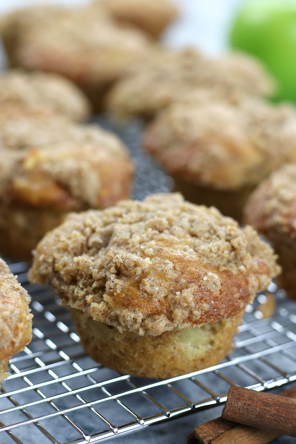 Up close vertical photo of Apple Crumble Muffins lined up on a cooling rack.