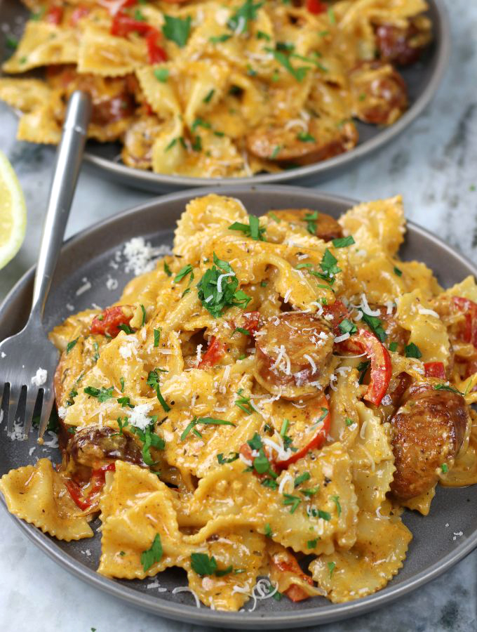 Two plates served with Cajun Pasta sitting on a white marble countertop.