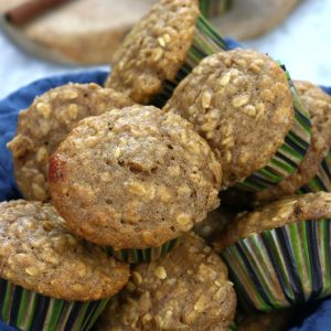 Oatmeal Cinnamon Muffins piled in a blue towel lines bowel.