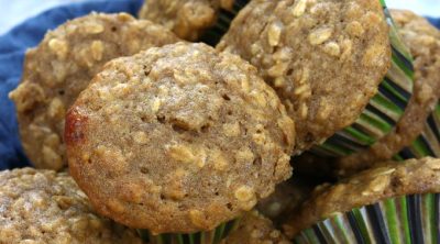 Oatmeal Cinnamon Muffins piled in a blue towel lines bowel.
