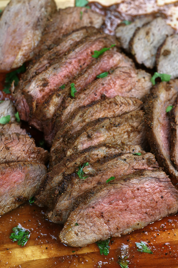 Roasted Tri-Tip sliced on a cutting board showing its medium-rare doneness.