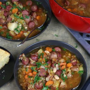 Overhead photo of two bowls of Sauerkraut Soup with carrots, sausage and beans.