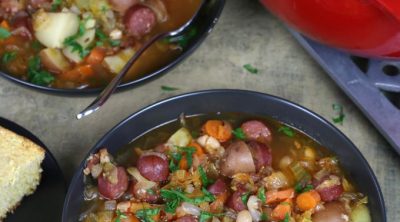 Overhead photo of two bowls of Sauerkraut Soup with carrots, sausage and beans.