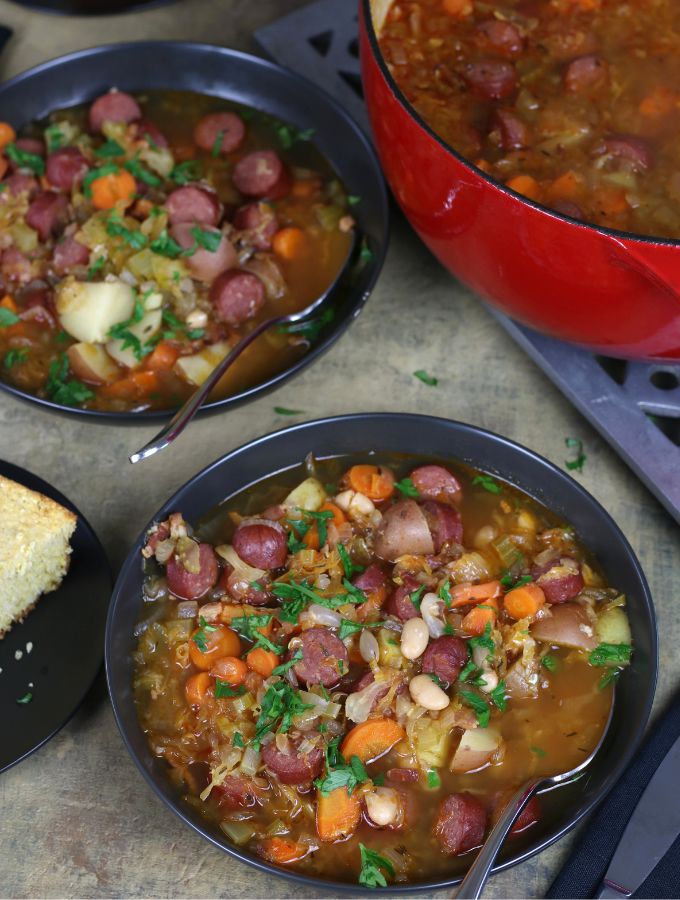 Overhead photo of two bowls of Sauerkraut Soup with carrots, sausage and beans.