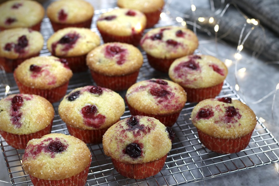 Prepared muffins from Fresh Cranberry Muffin Recipe on a cooling rack with white lights beside them.