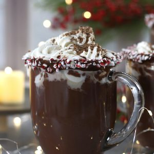 A mug of Homemade Hot Cocoa sitting in front of a Christmas decorations and candles.