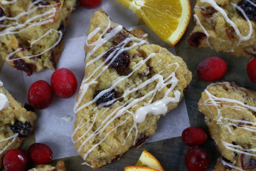 Cranberry Scones with dried cranberries, orange extract and orange zest surrounded by cranberries and orange slices.