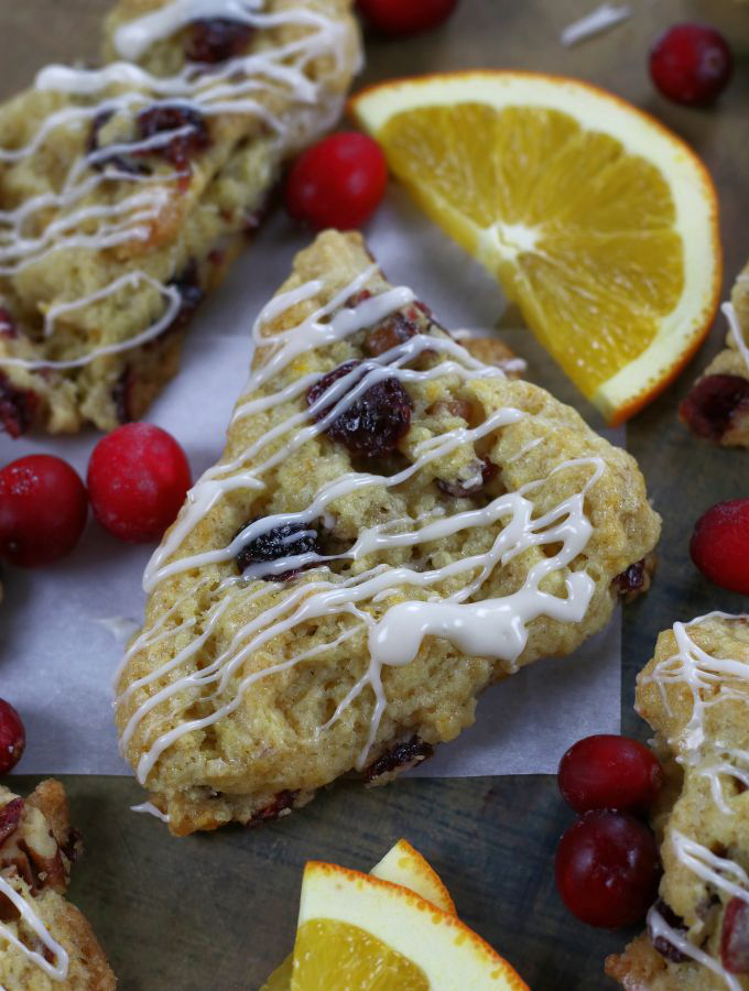 Orange Cranberry Scones surrounded by cranberries and orange slices.