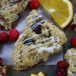 Up close photo of Orange and Cranberry Scones sprinkled with sparkling sugar and drizzled with a glaze.