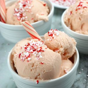 Three bowls of Peppermint Ice Cream with crushed candy canes and a peppermint stick.