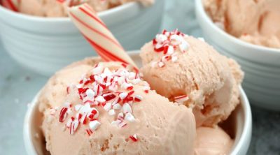 Three bowls of Peppermint Ice Cream with crushed candy canes and a peppermint stick.