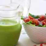 Cilantro Lime Salad Dressing in a salad dressing jar next to a bowl full of salad.