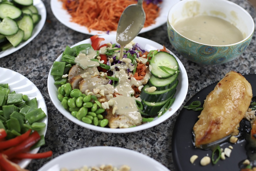 Buddha Bowl with Miso Chicken surround by the individual fixings for the Buddha bowl.