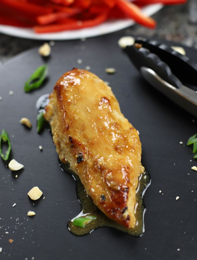 Miso Chicken breast sitting on a black cutting board.