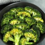 Easy Roasted Broccoli in a black bowl, lightly browned with a vibrant green color.