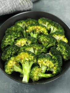 Overhead photo of a black bowl full of Roasted Broccoli florets.