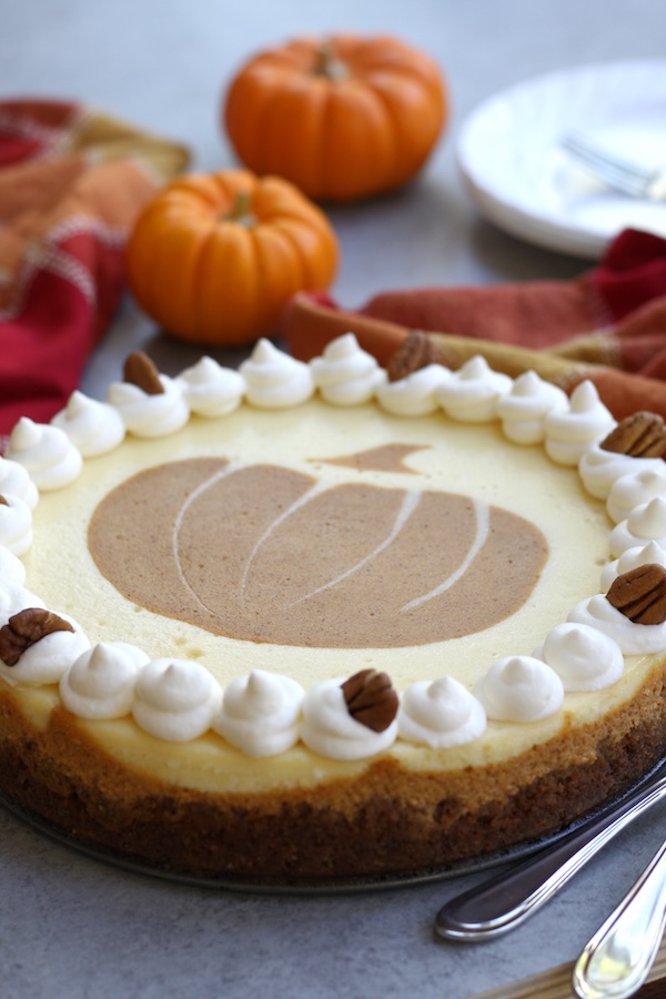 Double Layered Cheesecake garnished with whipped cream dollops and pecan halves.