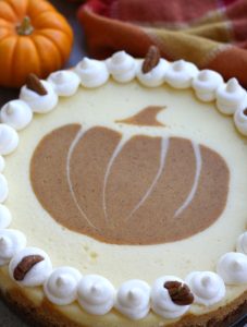 Double Layered Pumpkin Cheesecake with a pumpkin design made of pumpkin cheesecake filling on top of the cheesecake.