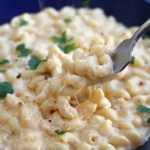 A forkful of Homemade Mac and Cheese being lifted from a blue bowl, showing tender pasta coated in rich cheese sauce.