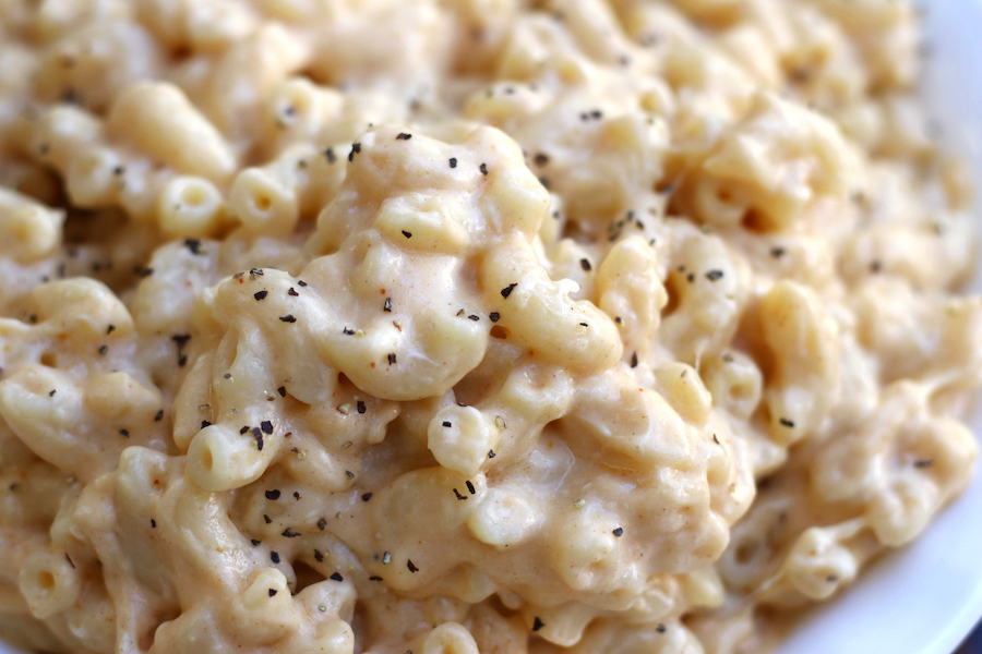 A bowl of golden, cheesy Macaroni and Cheese that’s perfectly creamy and dusted with black pepper.