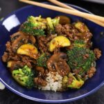 Ground Beef Teriyaki Stir Fry served in a royal blue bowl surrounded by green onion slices.