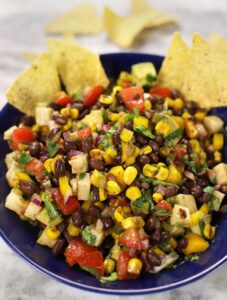 A blue bowl full of Black Bean and Corn Salad.