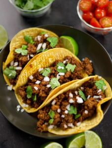 Ground Beef Taco Meat stuffed into yellow corn tortillas with chopped white onion and cilantro.