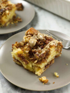 A slice of Sour Cream Coffee Cake on a light brown plate.
